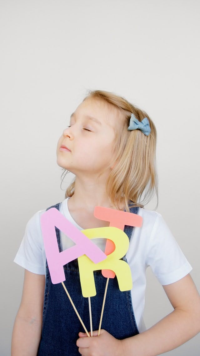 Child holding up ART letters